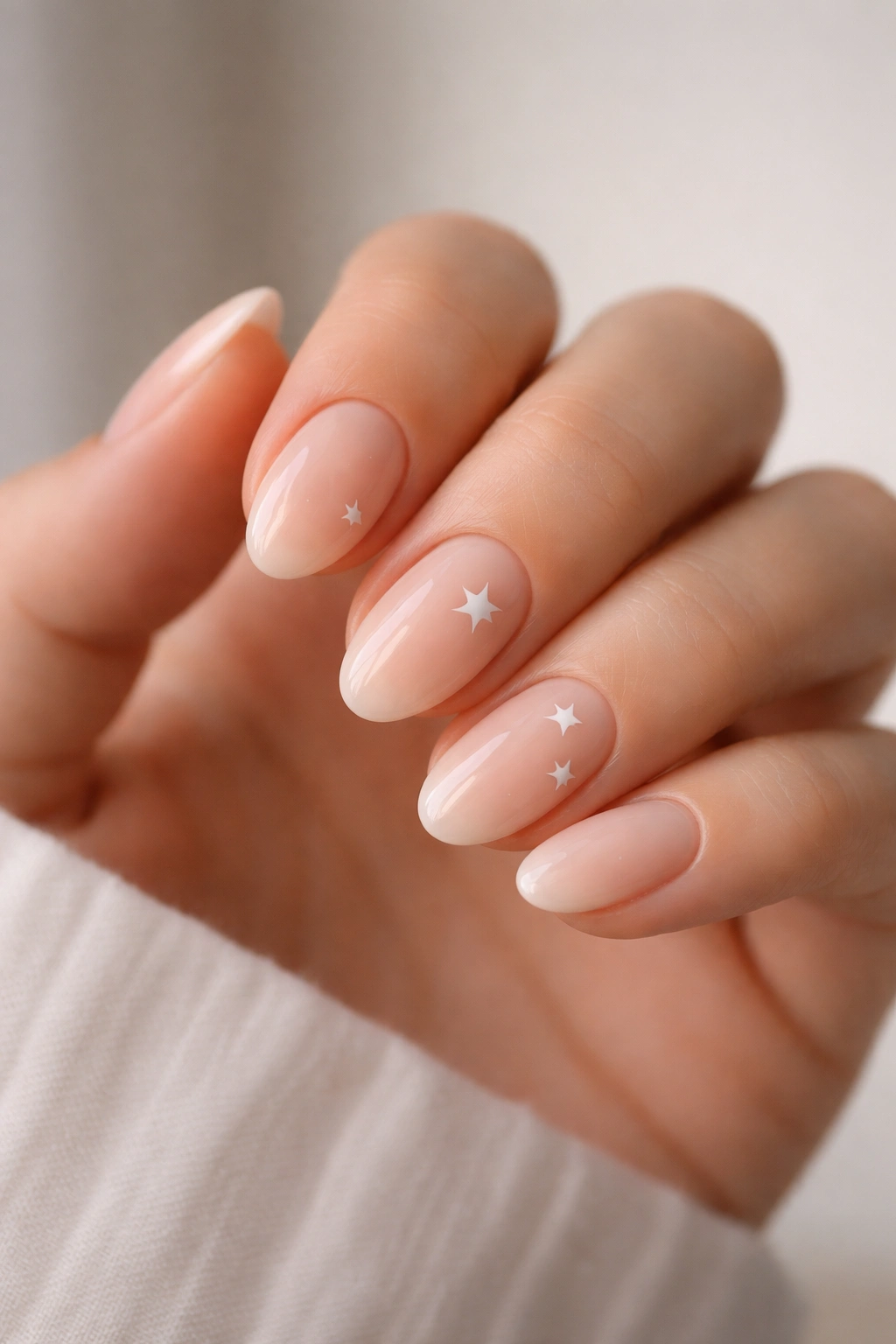 Close-up of short almond nails with star decals on a milky nude base