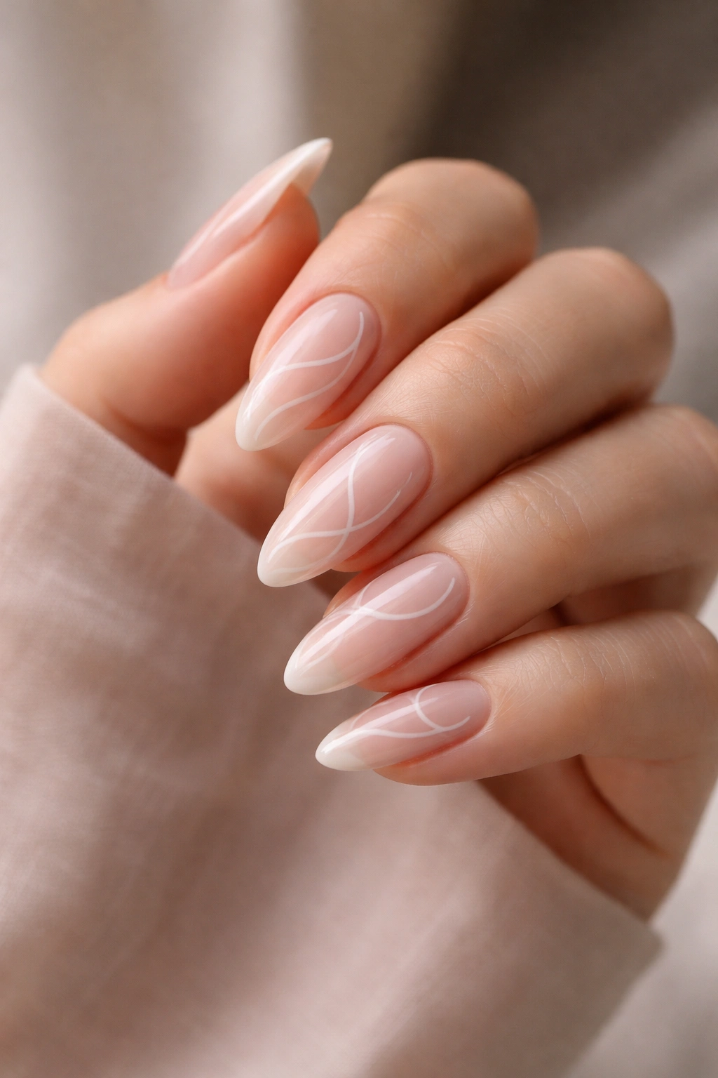 Close-up of almond nails with delicate swirl art on pink nude base