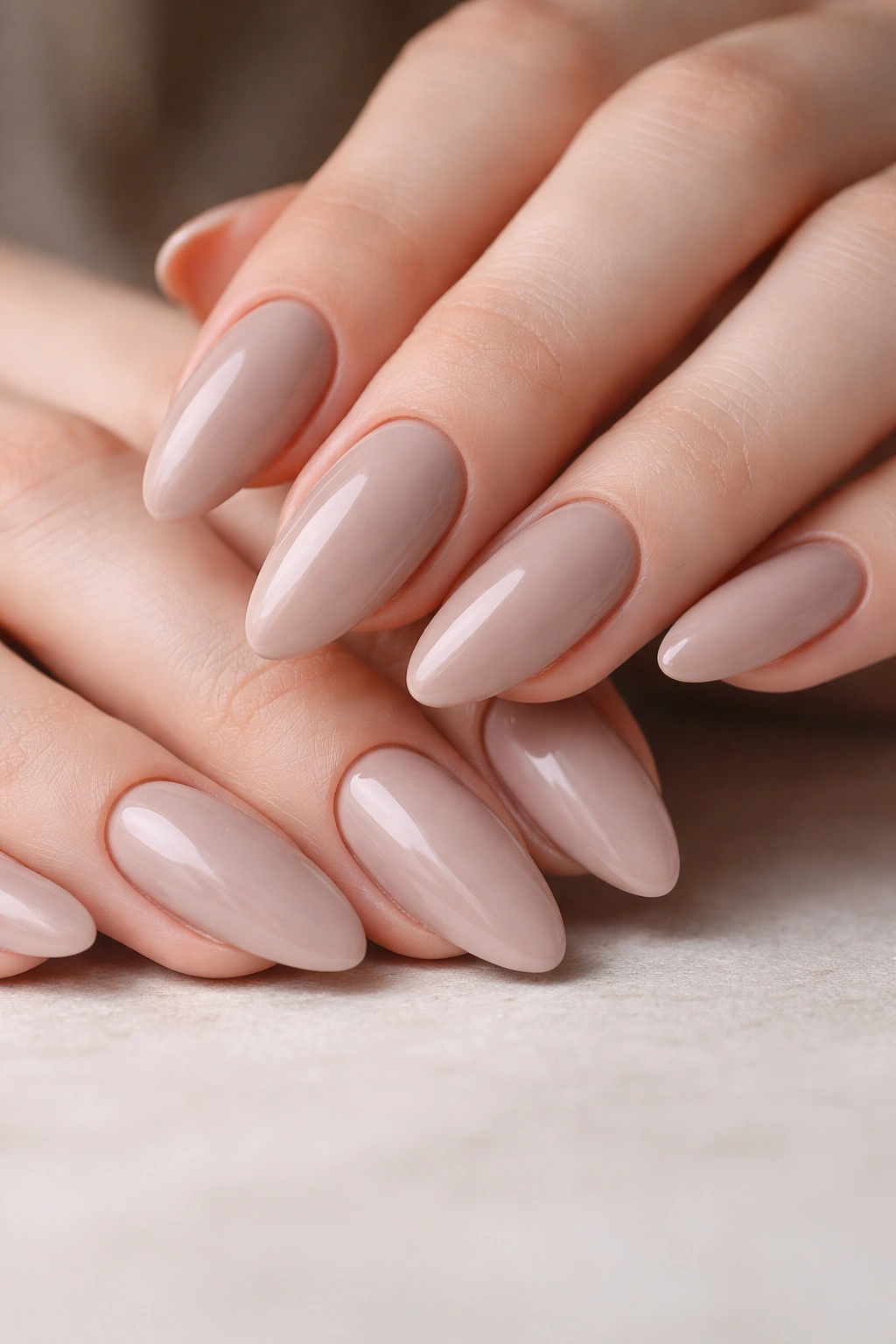 Close-up of almond nails painted in soft taupe with creamy finish