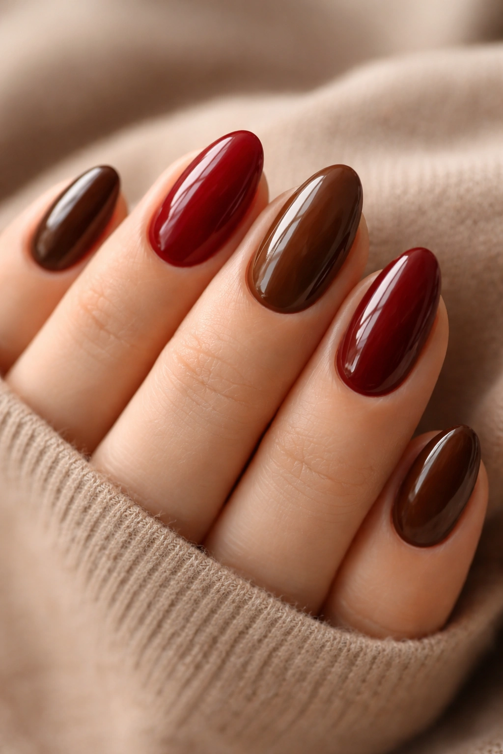 Close-up of short almond nails in a two-tone red and brown palette.