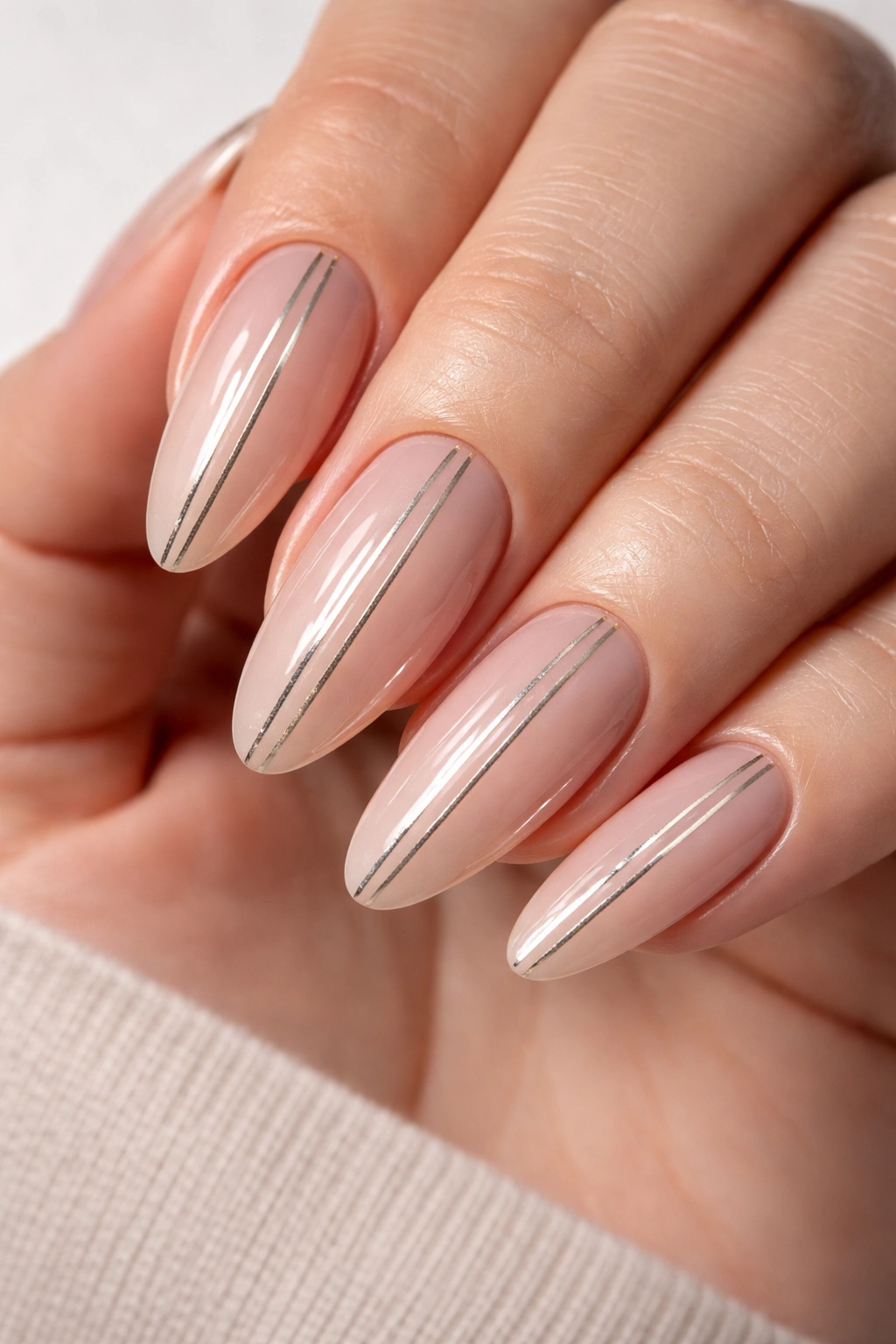 Almond nails with vertical gold stripes on nude base