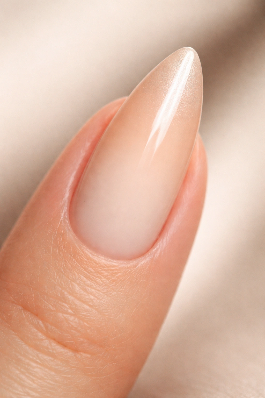 Close-up of an almond-shaped nail with a seamless ombre gradient on a neutral background.