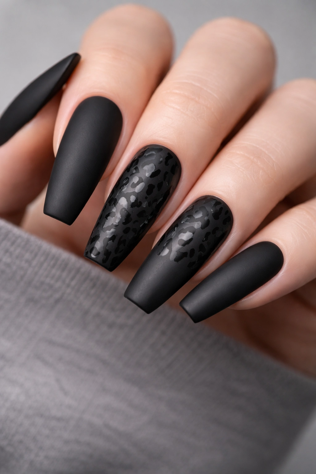 Close-up of matte black nails with glossy animal-print accents