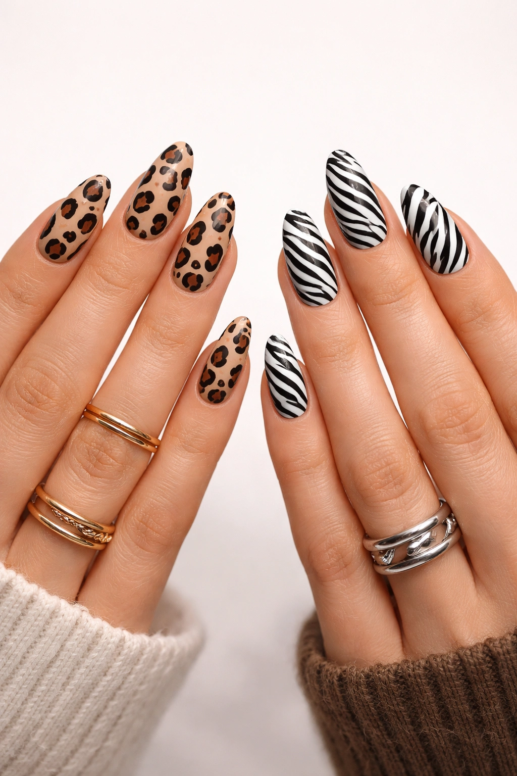 Two hands showing different animal print nail designs, leopard and zebra, on coordinated manicures.