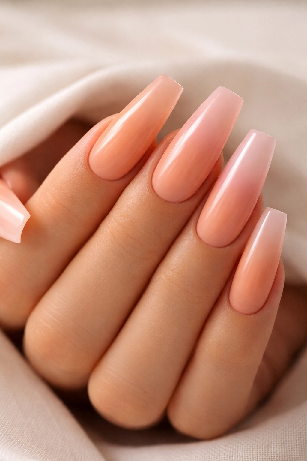 Close-up of coffin nails in warm apricot to nude pink ombre.