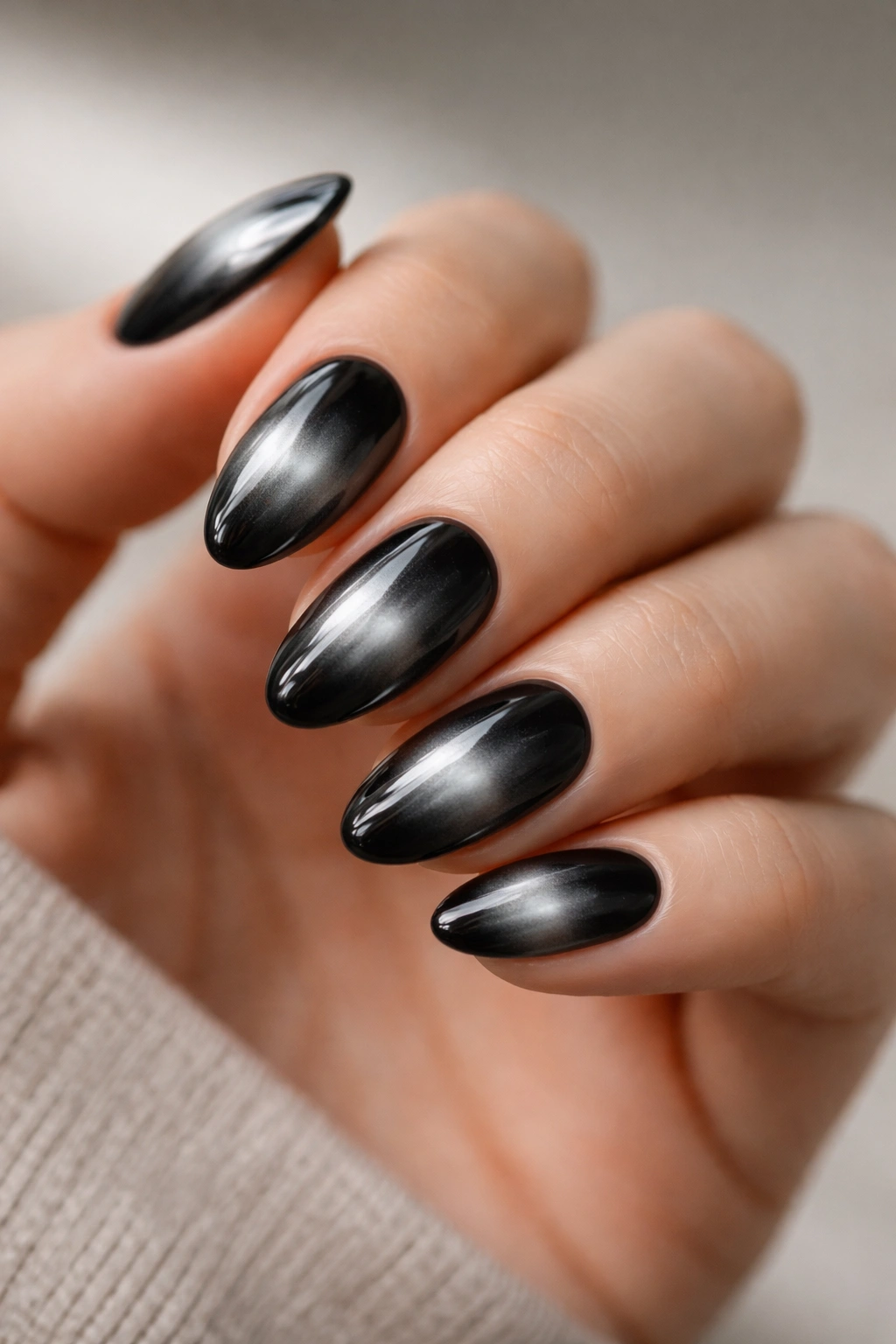 Close-up of short almond nails with center-diffused aura glow on black chrome