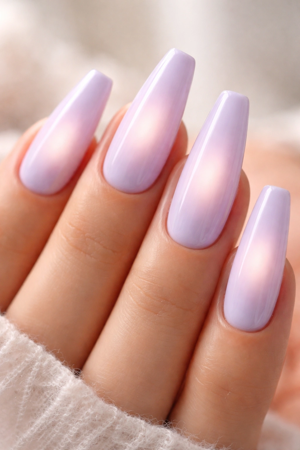 Close-up of ballerina nails with pale lilac base and blurred center glow