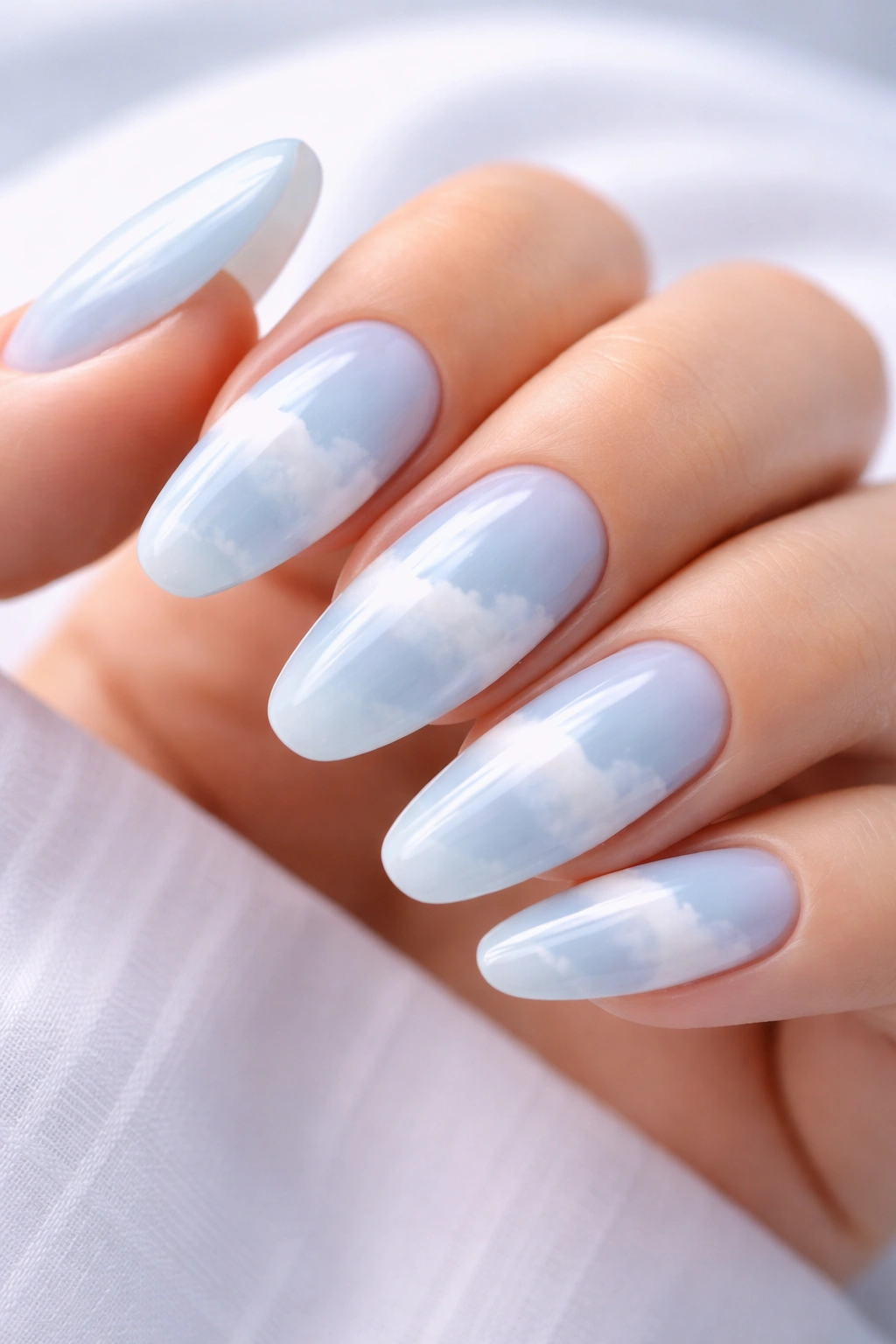 Close-up of light blue aura nails with gradient cloud design