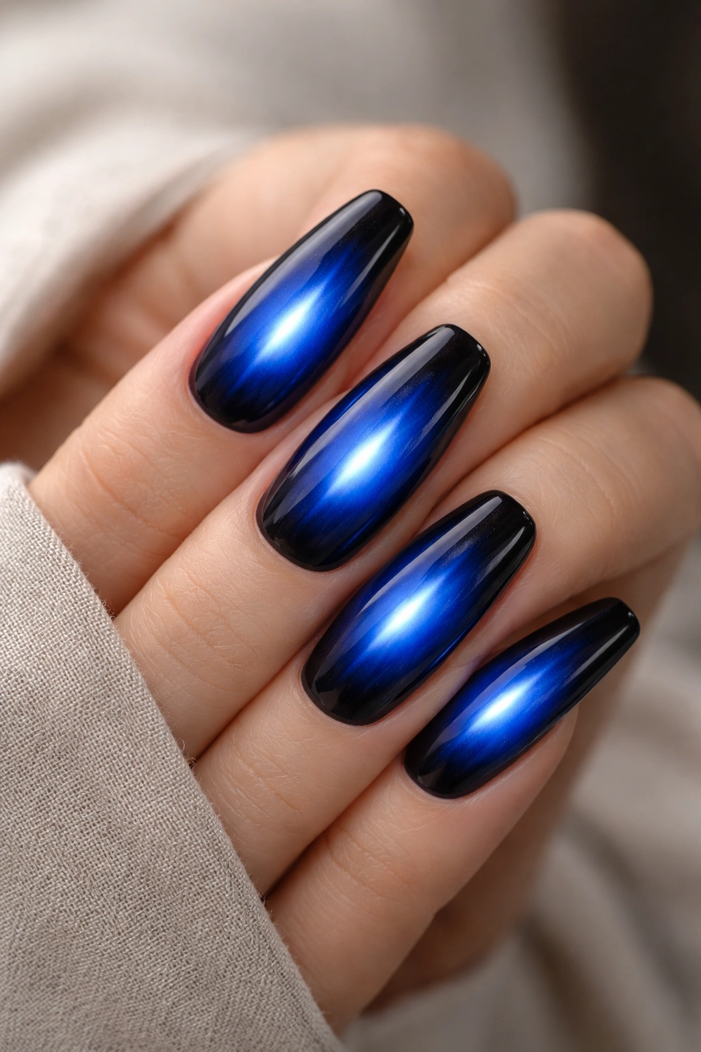 Close-up of dark blue aura nails with electric cobalt center glow on ballerina nails