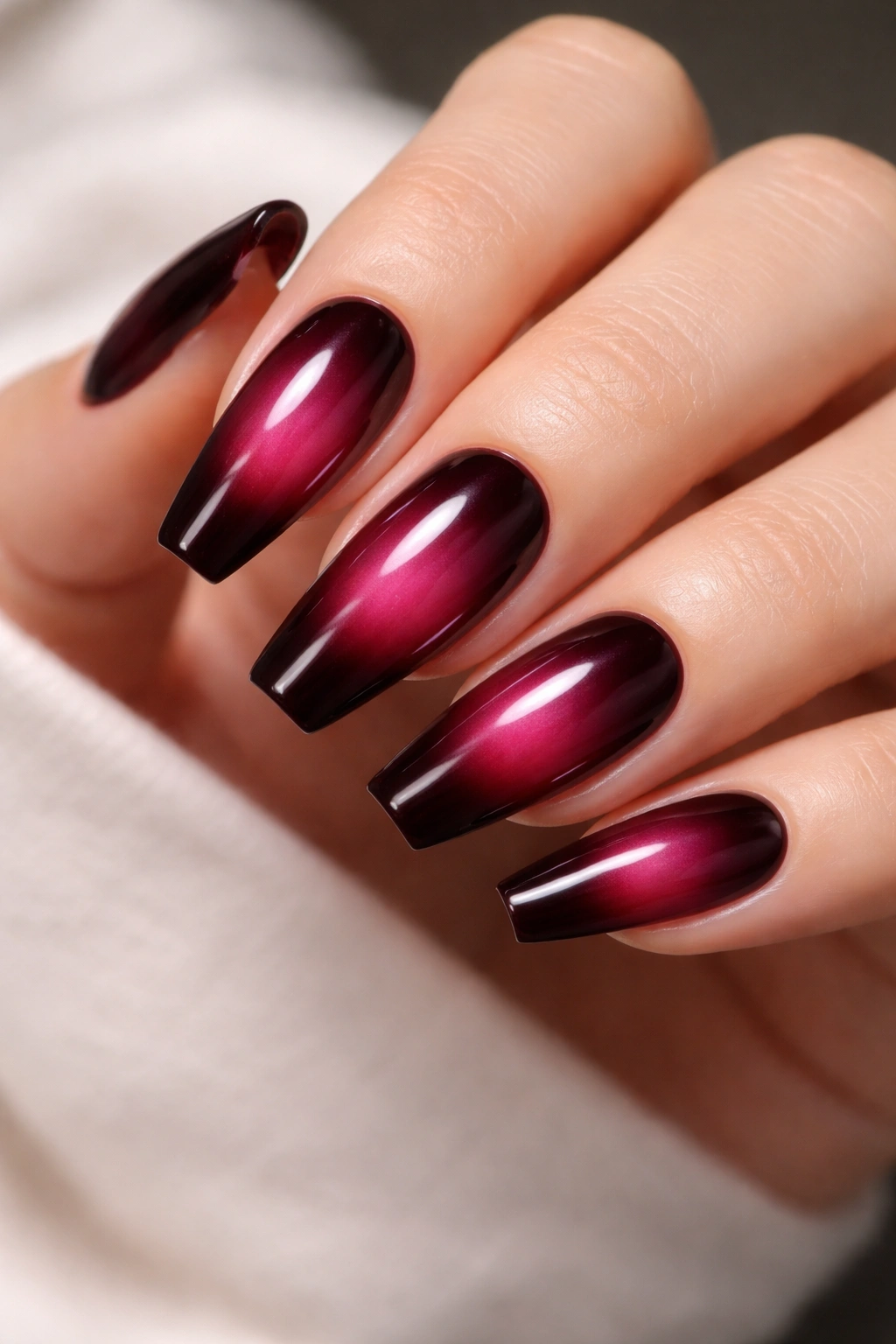 Plum-red aura nails with centered glow on ballerina shape.
