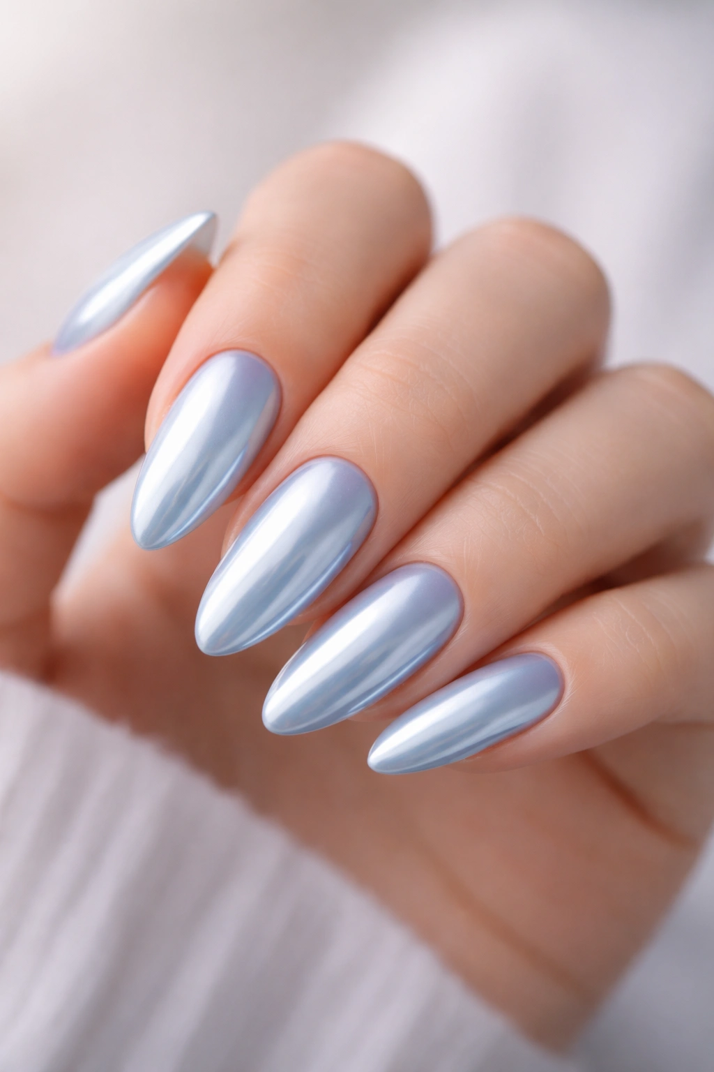 Close-up of almond nails with a soft baby blue chrome finish.