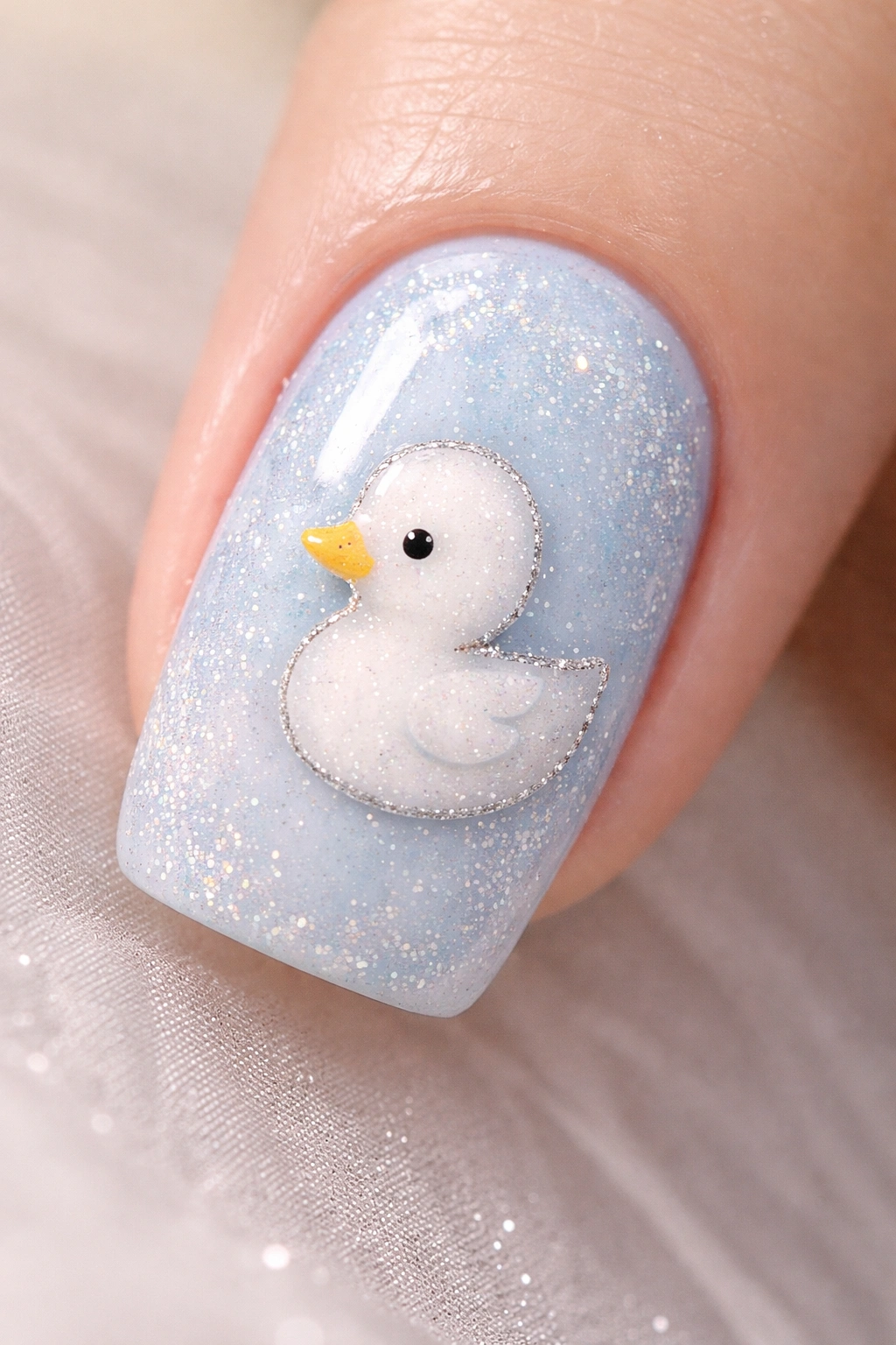 Close-up of a baby blue nail with a white duck silhouette and glitter detail