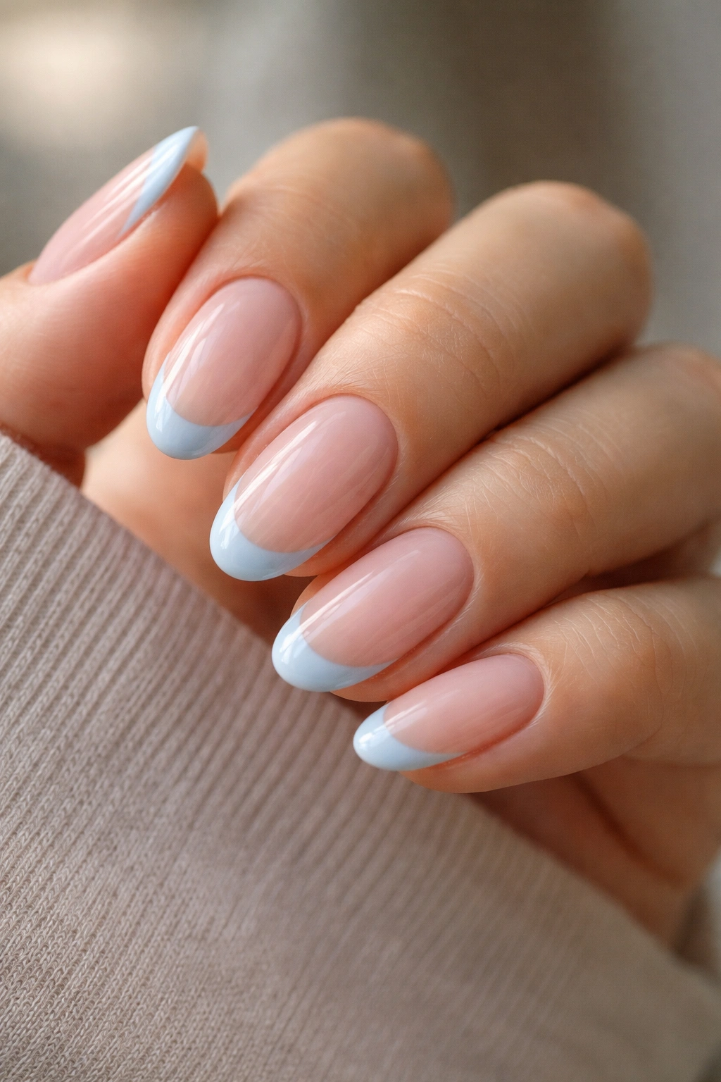 Close-up of short almond nails with sheer base and baby blue tips