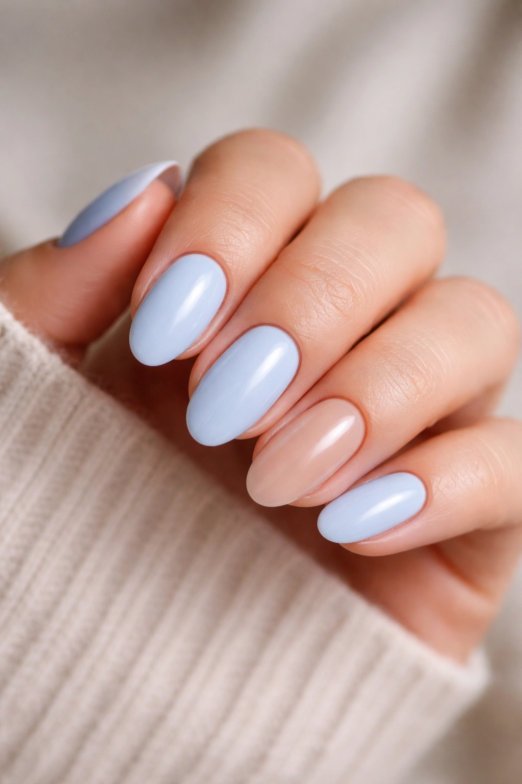 Close-up of baby blue nails with a single bare accent nail on a short almond manicure.