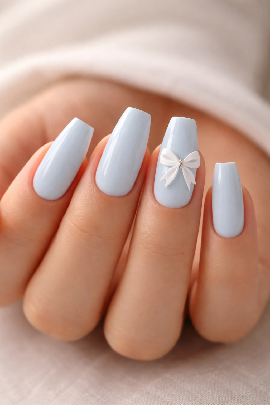 Close-up of baby blue ballerina nails with off-center white bow accents