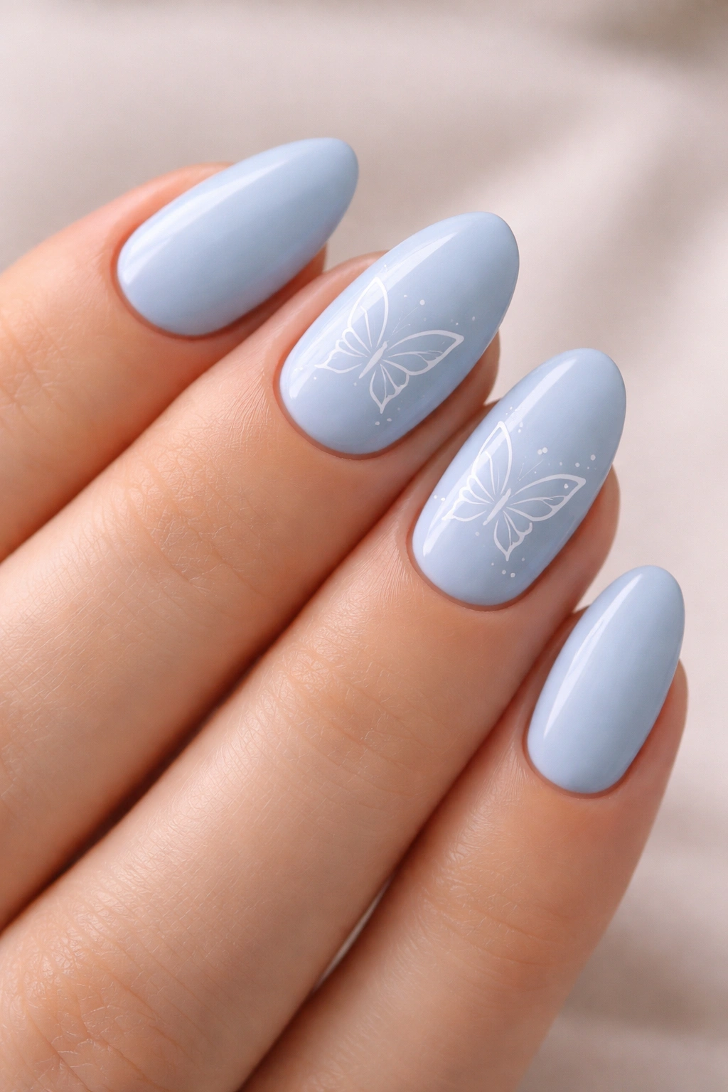 Short almond nails in baby blue with white butterfly line art on several nails