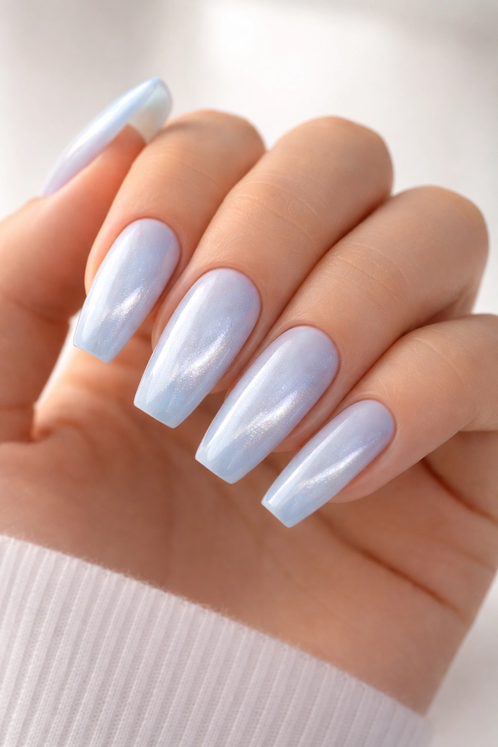 Close-up of baby-blue cat-eye ballerina nails with diagonal shimmer on a neutral background