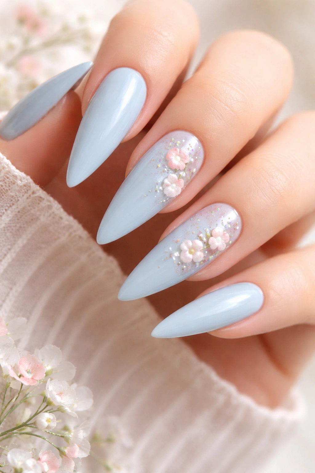 Close-up of baby blue stiletto nails with delicate white and pink florals