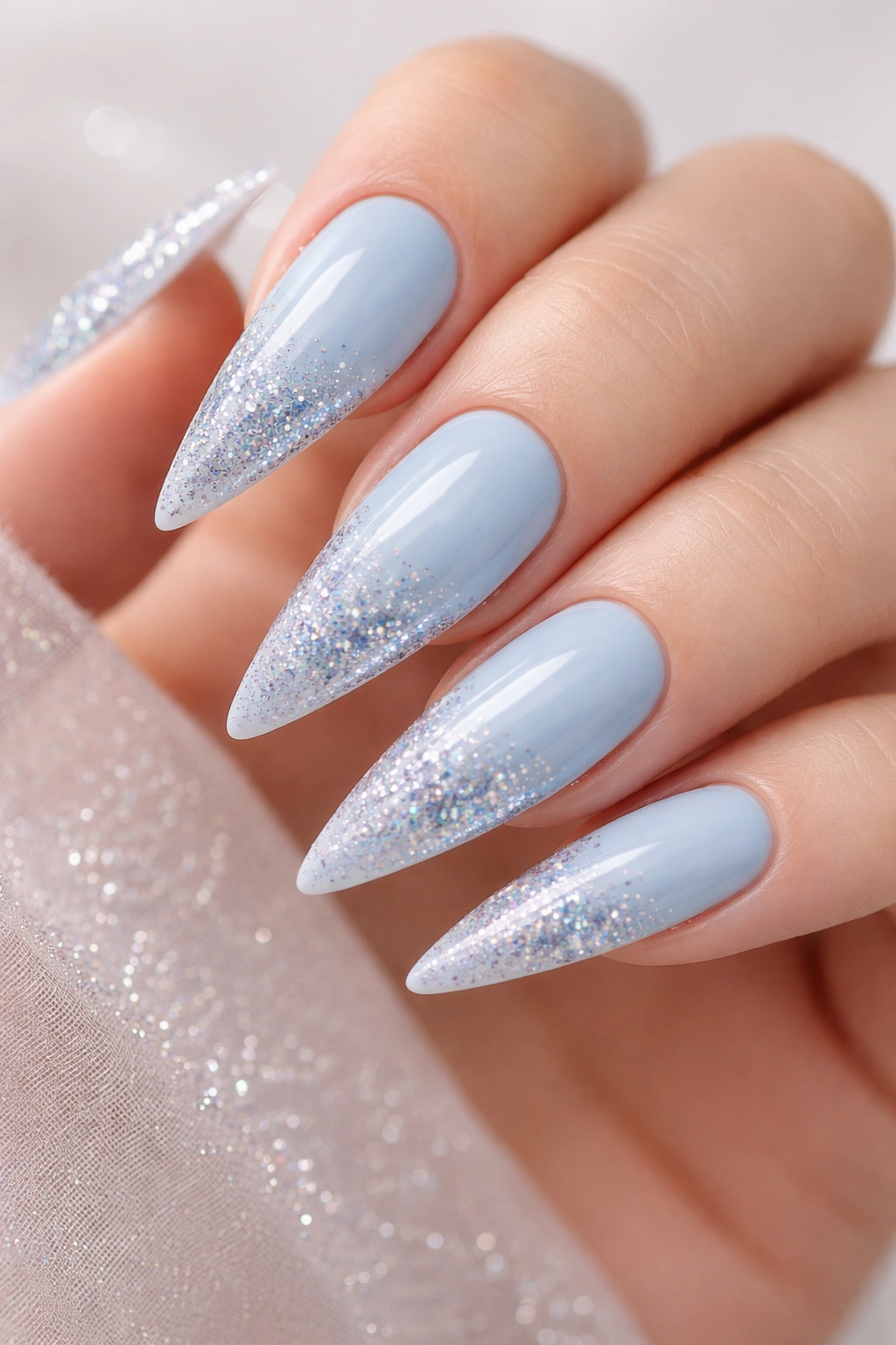 Close-up of baby blue stiletto nails with glitter accents
