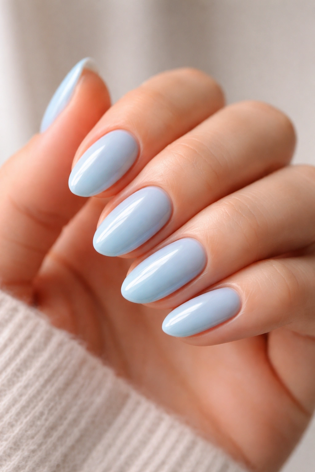 Close-up of short almond nails with creamy baby blue and high-gloss finish