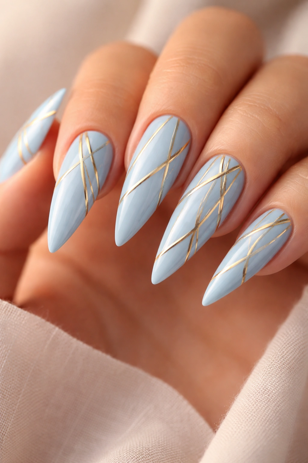 Close-up of baby blue stiletto nails with gold geometric patterns
