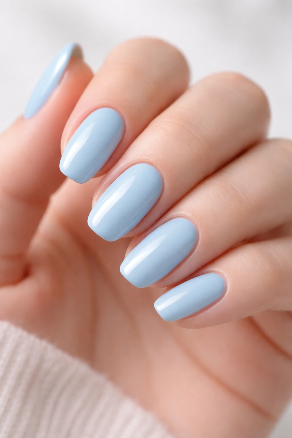 Close-up of baby blue nails on a hand with glossy finish in neutral lighting