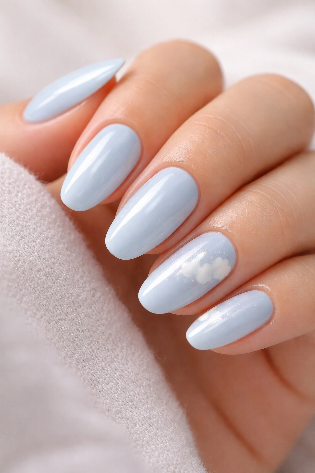 Close-up of baby blue nails with subtle cloud accents