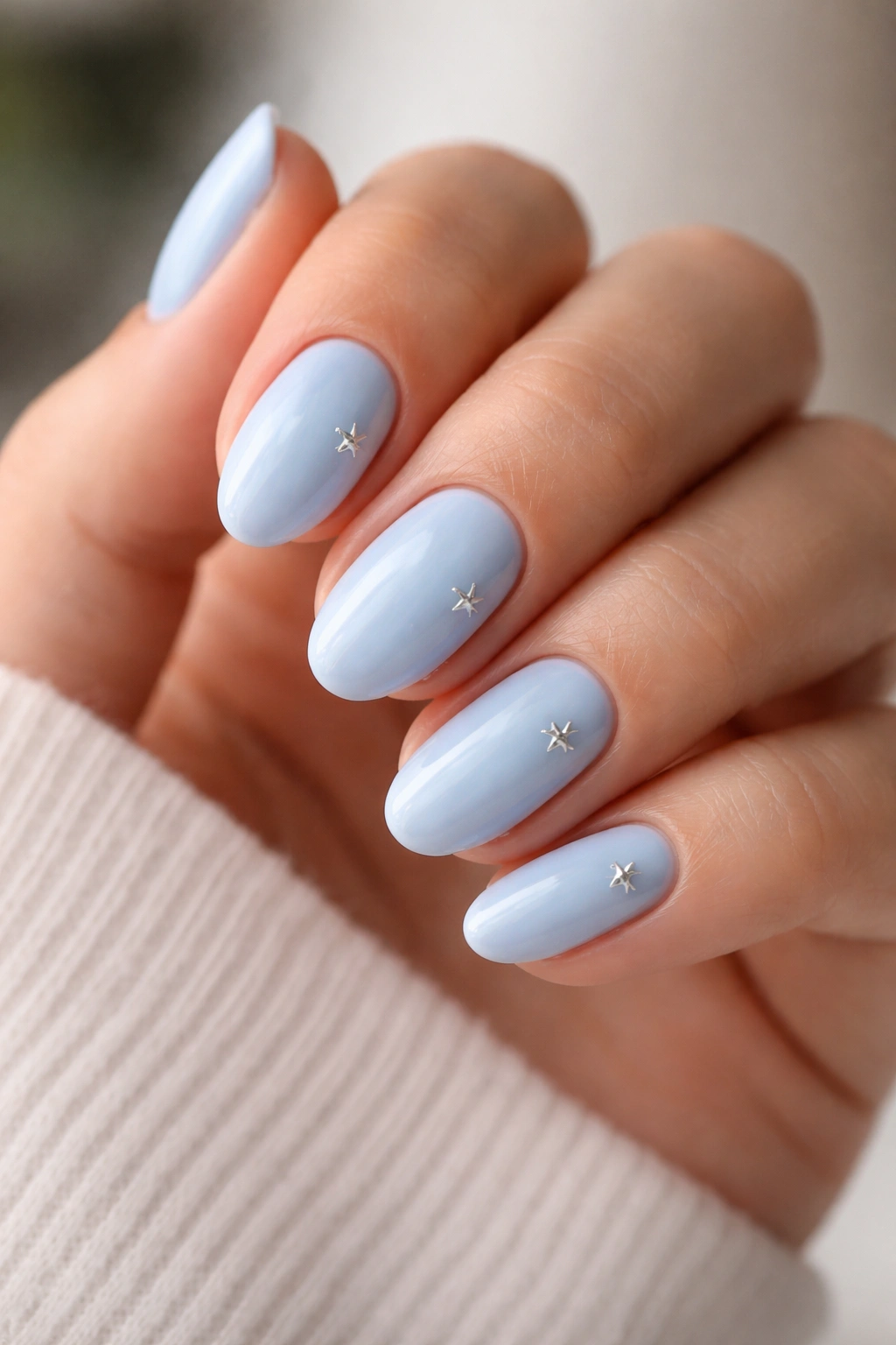 Close-up of baby blue nails with tiny silver stars on short almond nails