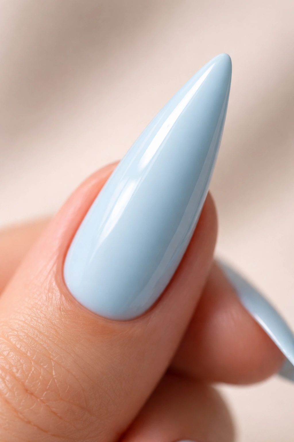 Close-up of a single baby blue stiletto nail with a glossy pastel finish