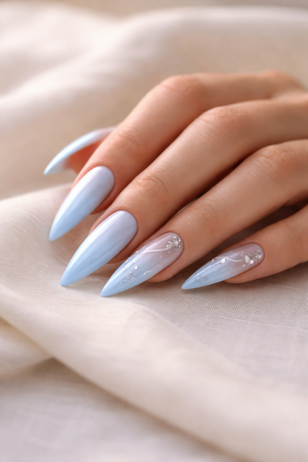 Close-up of polished baby blue stiletto nails on a neutral surface