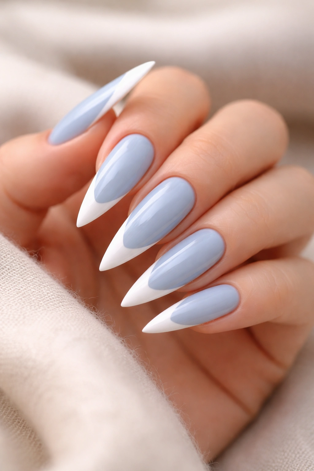 Close-up of baby blue stiletto nails with crisp white tips on a hand.