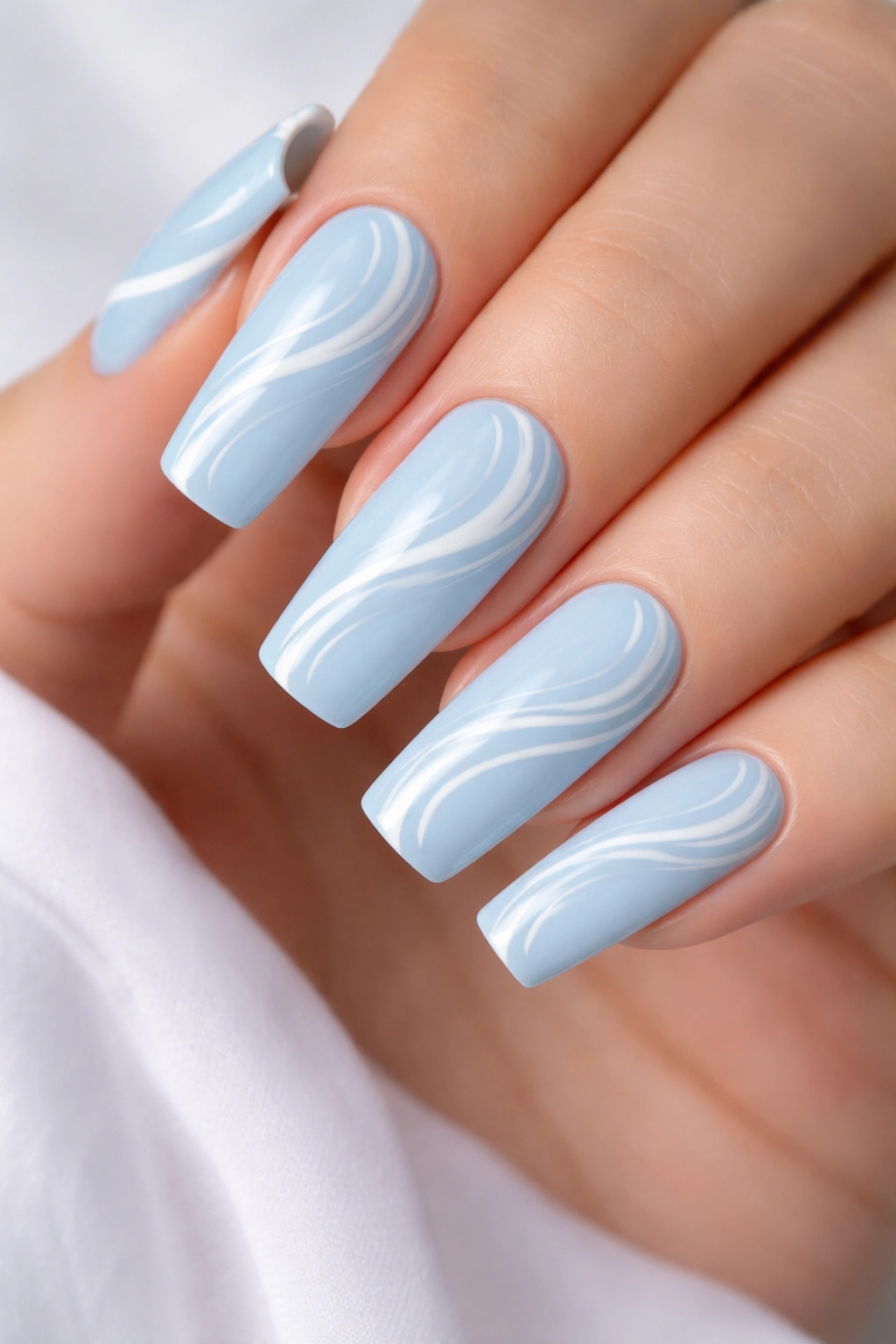 Close-up of long squoval nails in baby blue with white swirl