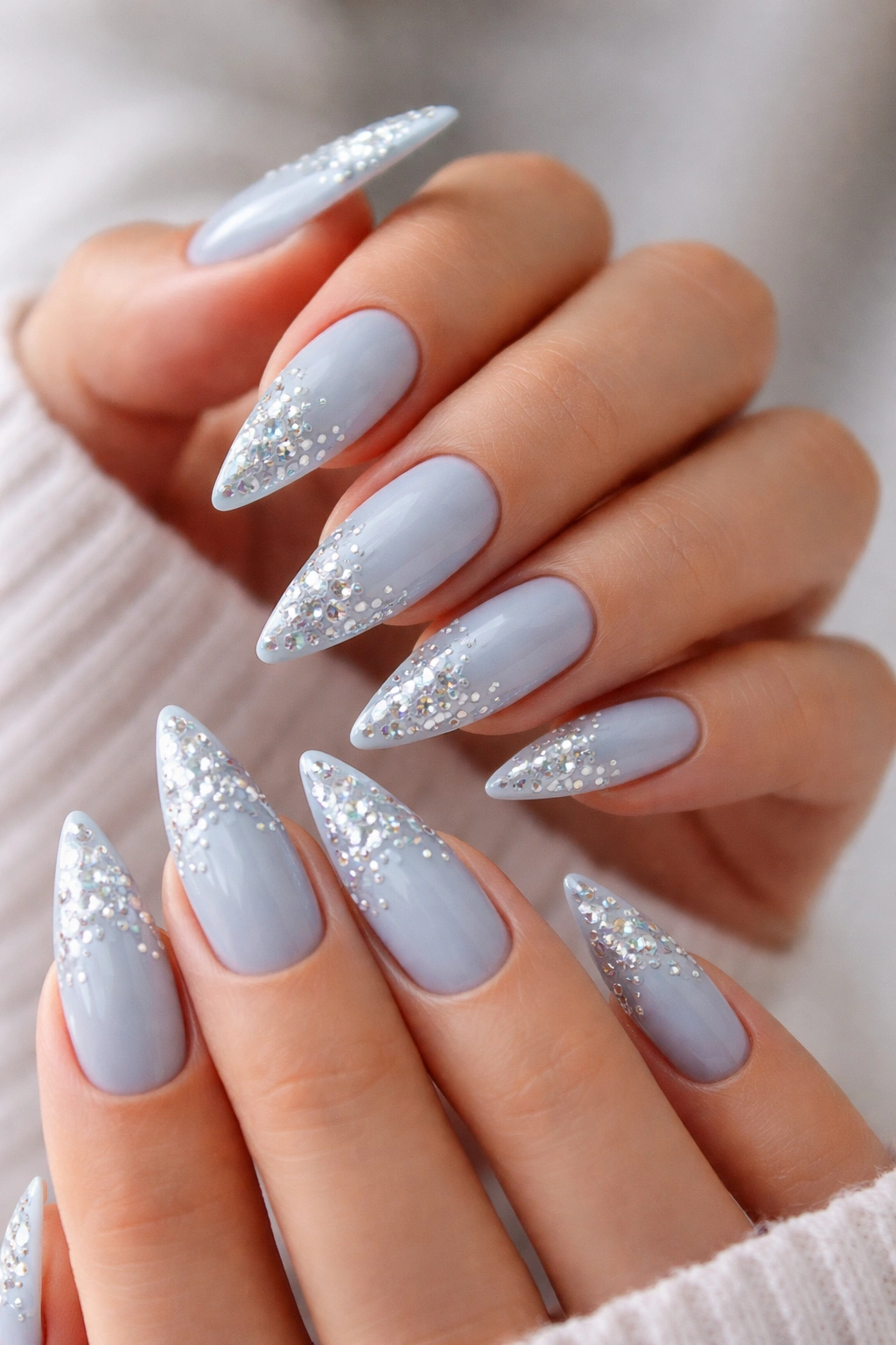 Close-up of stiletto nails with icy blue base and rhinestone accents