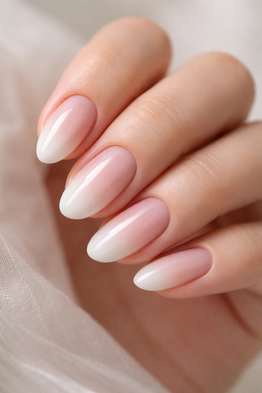 Close-up of short almond nails with soft pink to white gradient