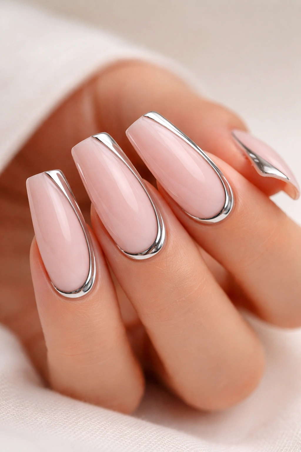 Close-up of duck-nail nails with a creamy pink base and chrome accents along the cuticle