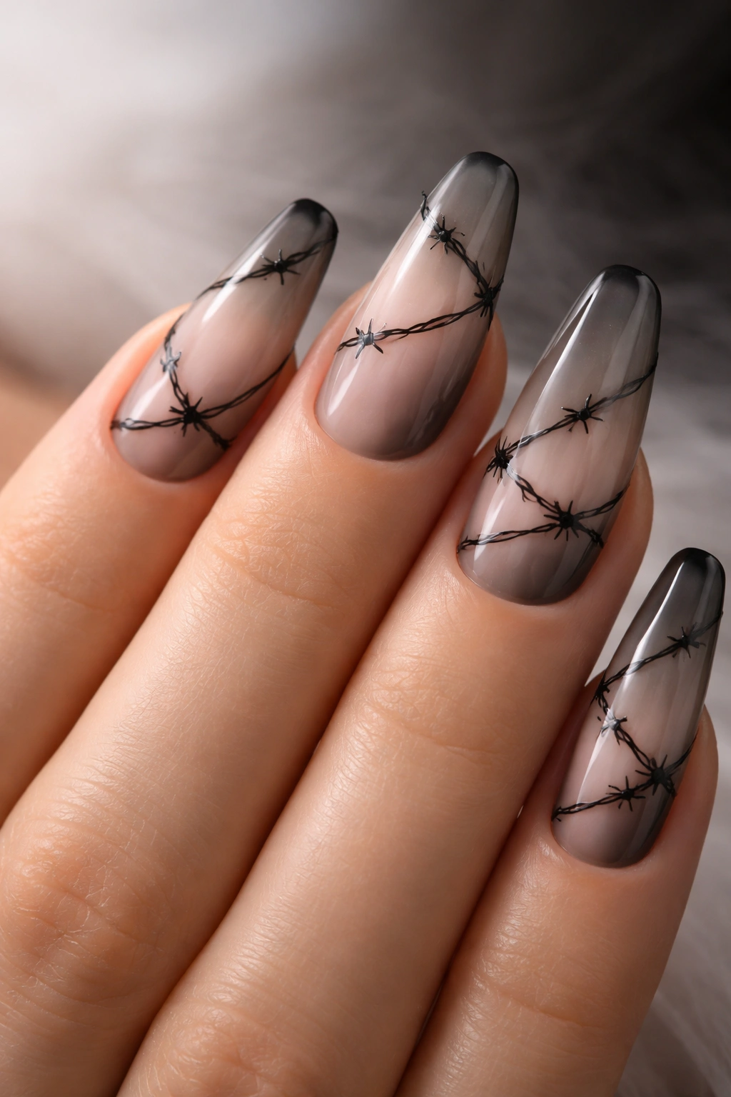 Close-up of black barbed wire line art on smoky nude nails