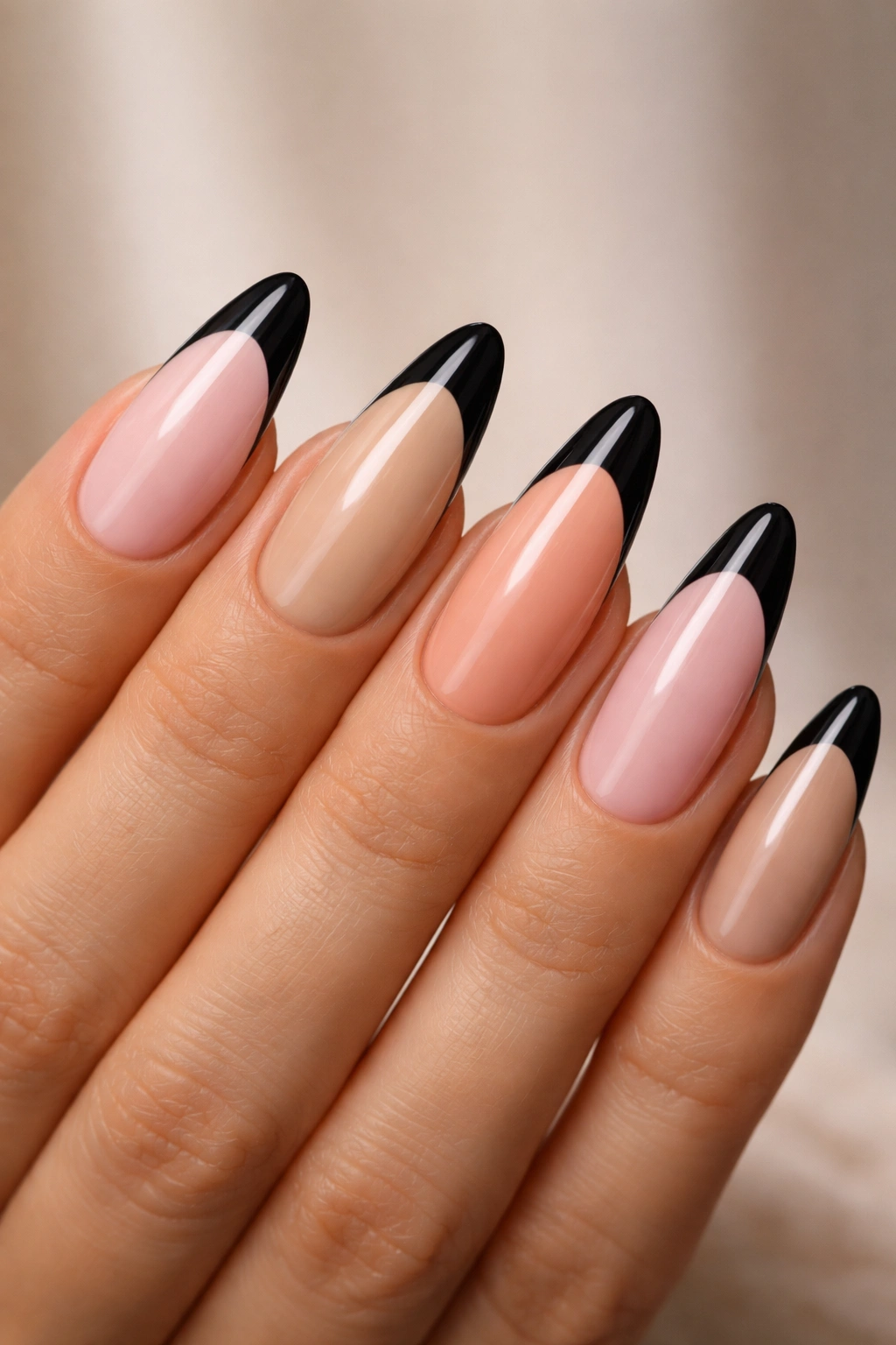 Almond nails with black tips showing varied base colors including pink, beige, and nude shades.