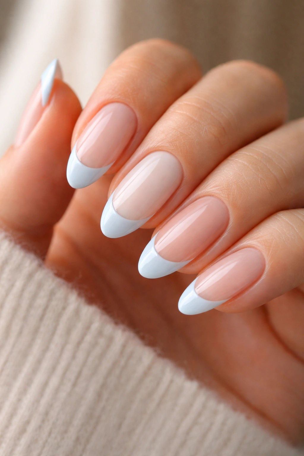 Hand displaying nails with multiple base colors under a light blue French tip