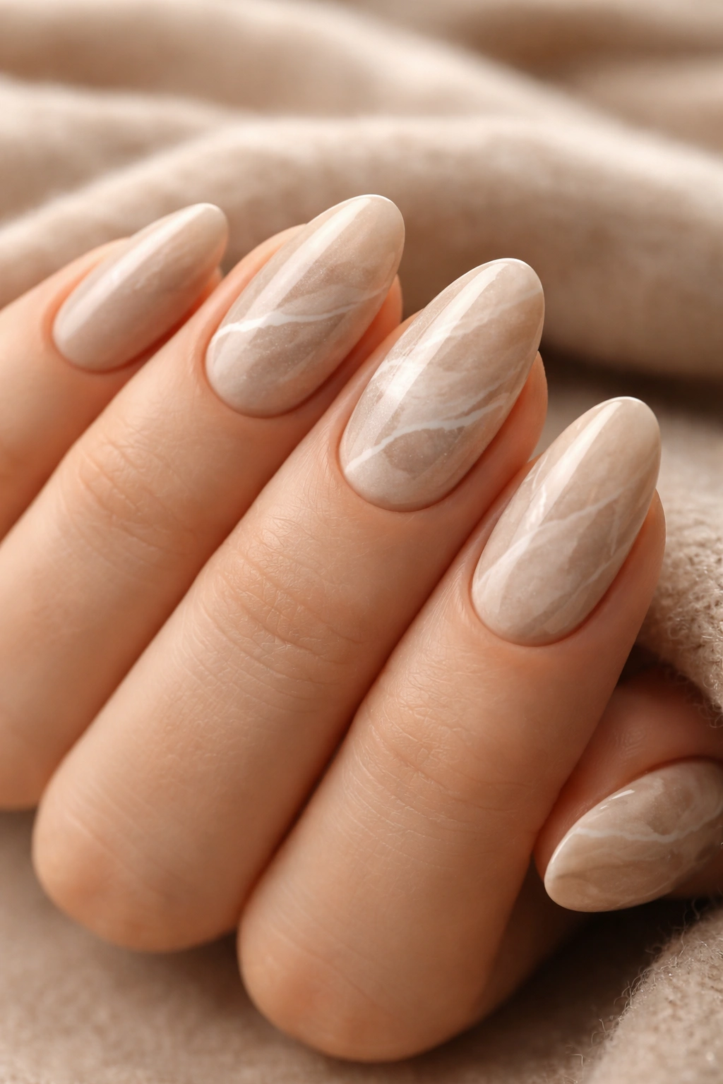 Close-up of beige marble nails on short almond tips with a cashmere-like finish