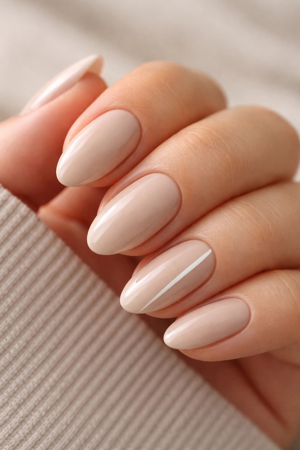 Close-up beige almond nails with a single glossy stripe