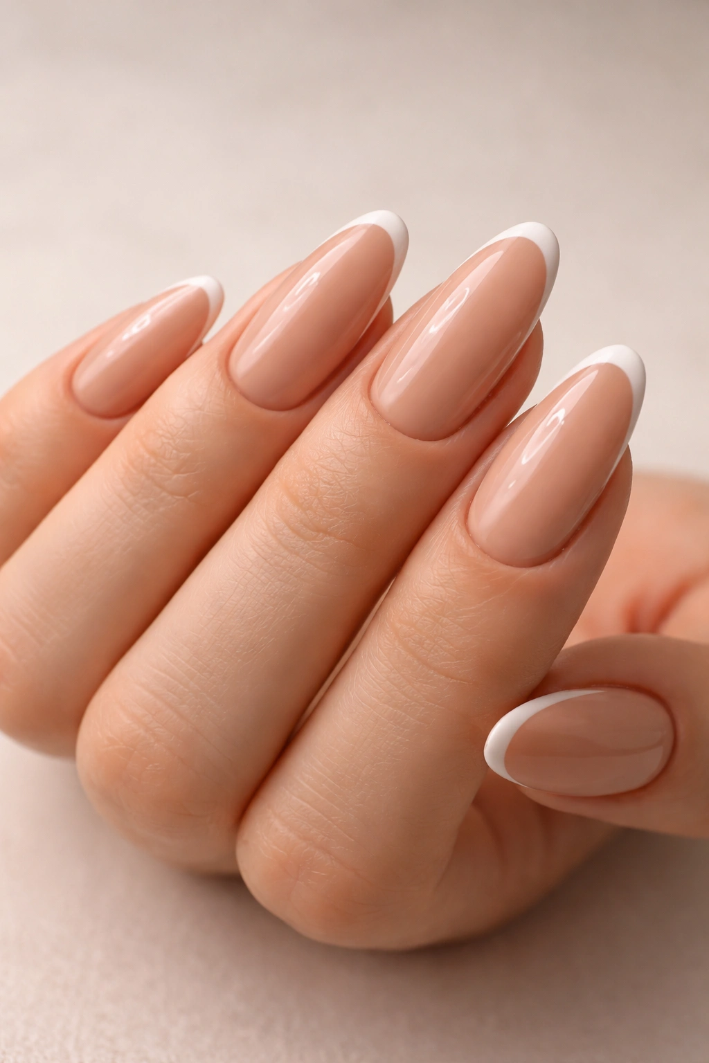 Close-up of warm beige oval nails with a thin white curved smile line