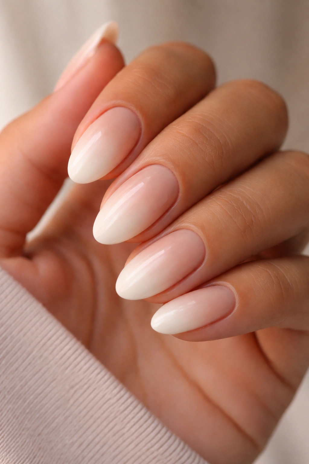 Close-up of short almond nails with beige nude to cream ombre dip powder