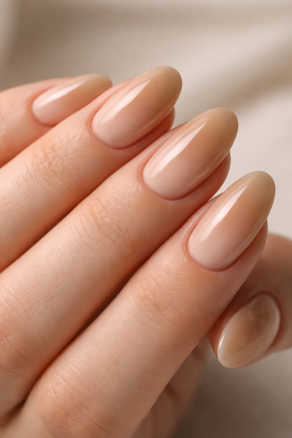 Close-up of almond nails with beige ombre and glossy glaze