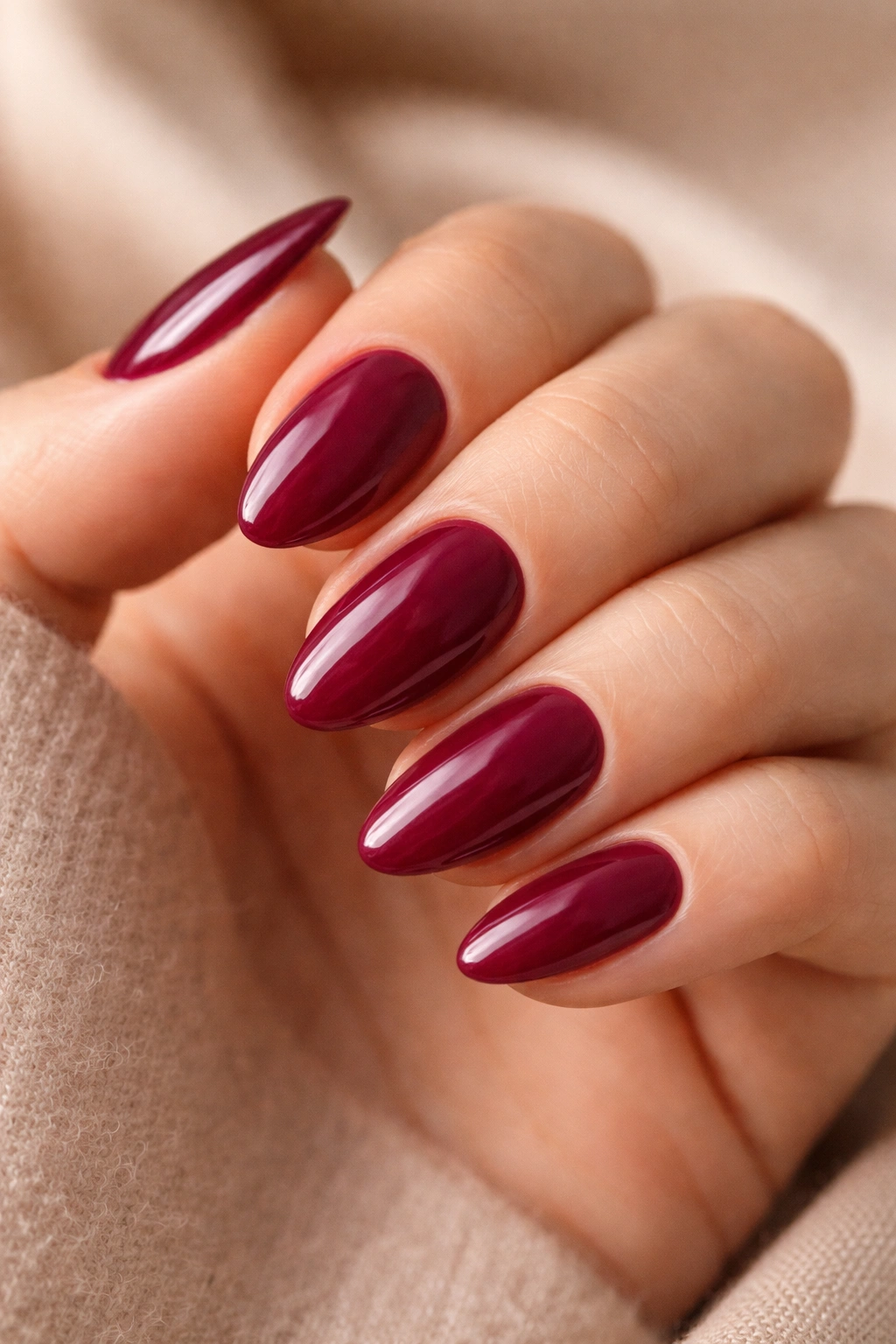 Close-up of short almond nails in deep berry shade