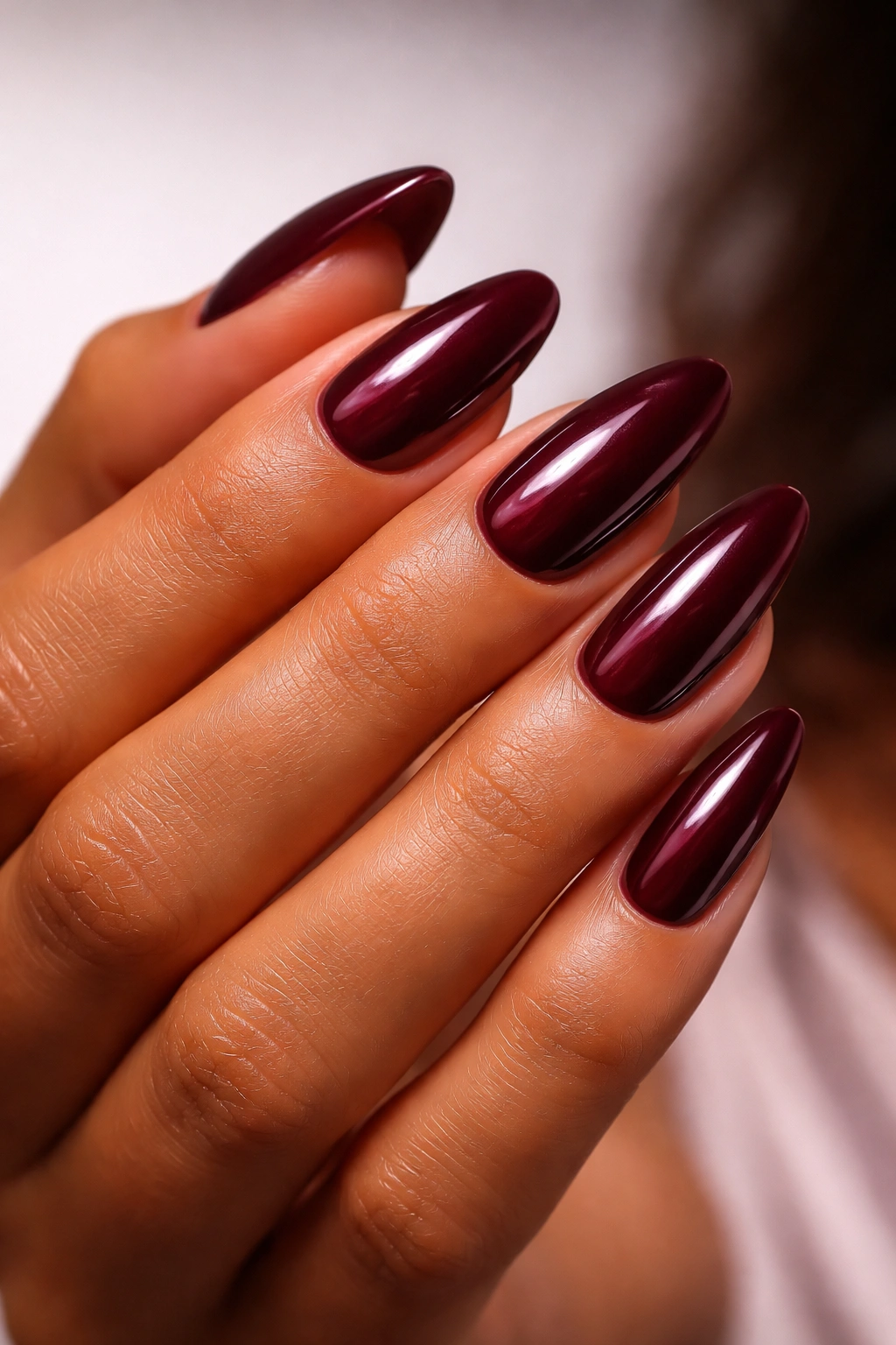 Close-up of burgundy berry nails on tan skin