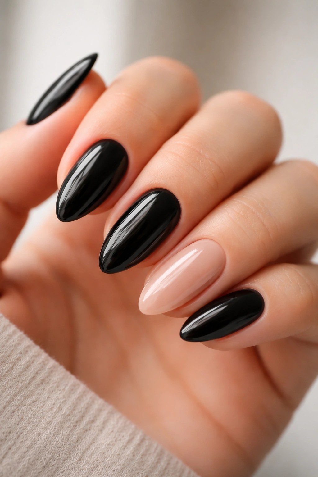 Close-up of black almond nails with one bare accent nail