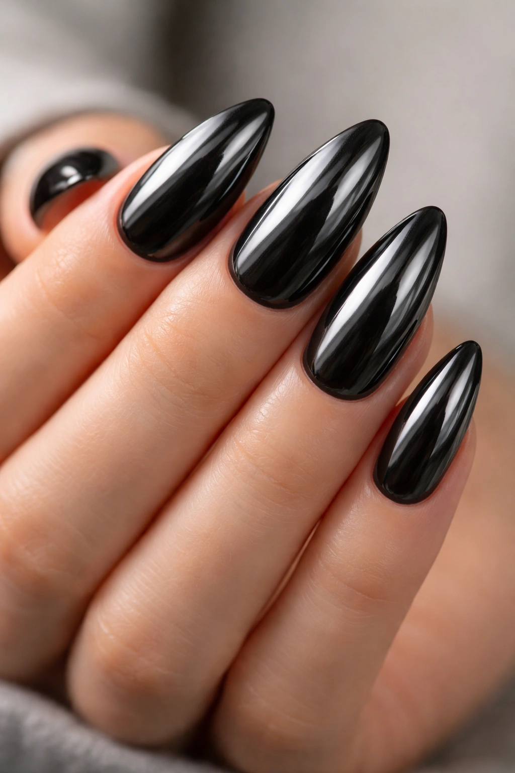 Close-up of black almond nails with chrome mirror finish