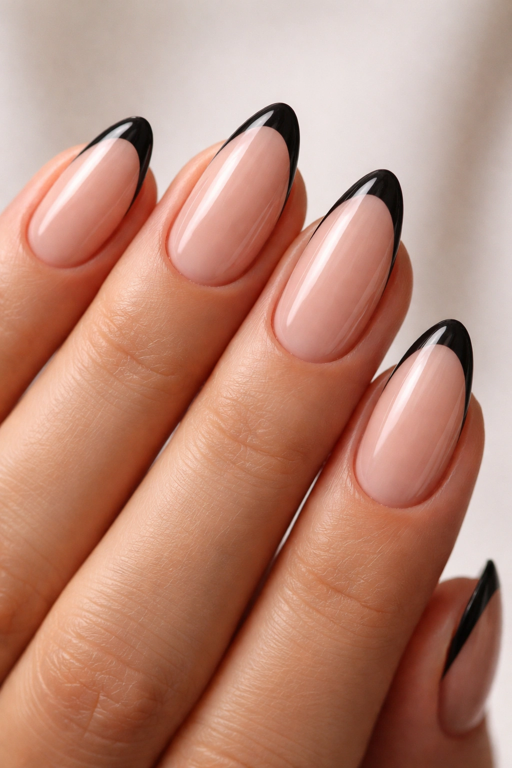 Close-up of black almond nails with ultra-thin micro French tips on nude base