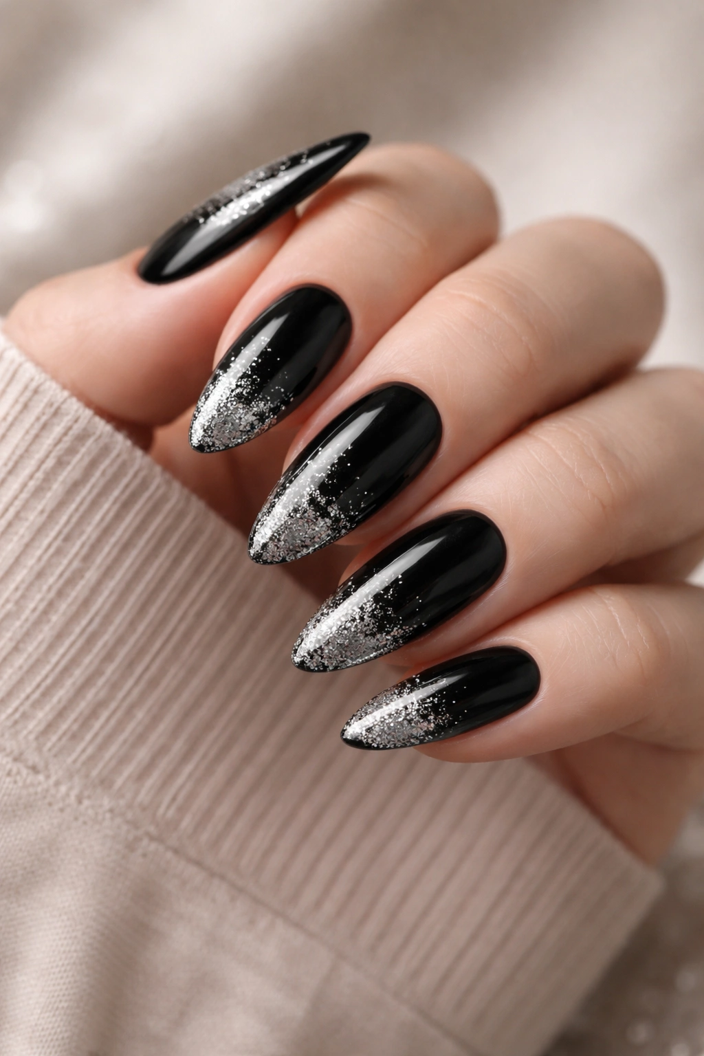 Close-up of black almond nails with a silver glitter fade and glossy finish
