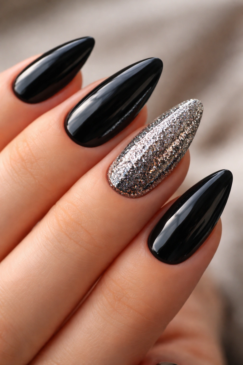 Black almond nails with a dense glitter accent nail on the ring finger